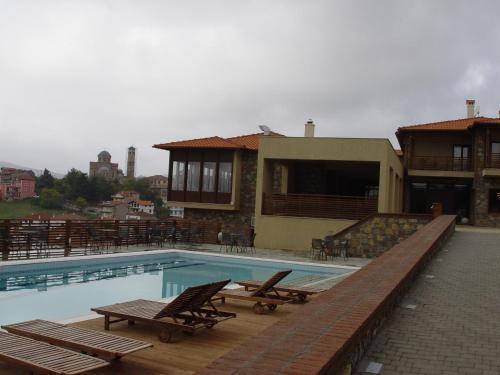 una piscina con 2 sillas y una casa en Iberis Hotel, en Siátista