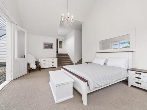 een witte slaapkamer met een bed en een kroonluchter bij Blairgowrie Hamptons Style in Blairgowrie