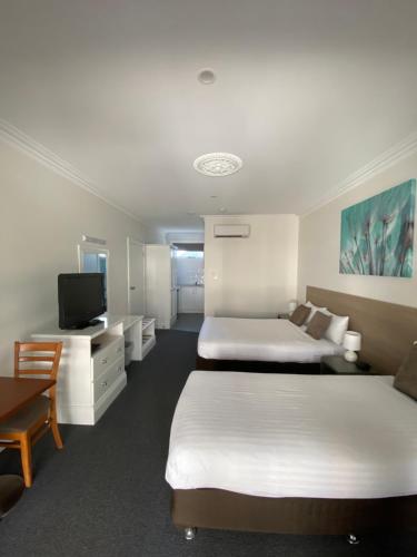 Habitación de hotel con 2 camas y TV de pantalla plana. en Campaspe Lodge, en Echuca