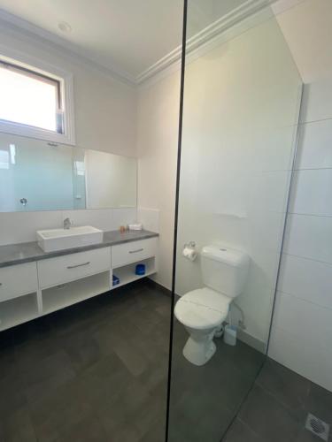 a bathroom with a toilet, sink, and shower stall at Campaspe Lodge in Echuca