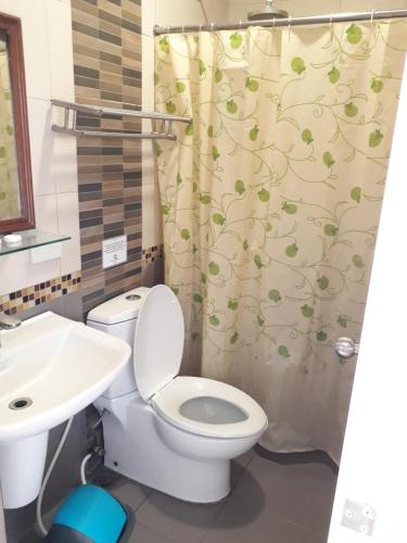 a bathroom with a toilet and a shower curtain at Sea Garden Resort Iloilo in Iloilo City