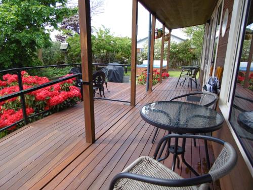 a porch with a table and chairs and flowers at Blue Ridge Studios and Bed & Breakfast in Te Anau