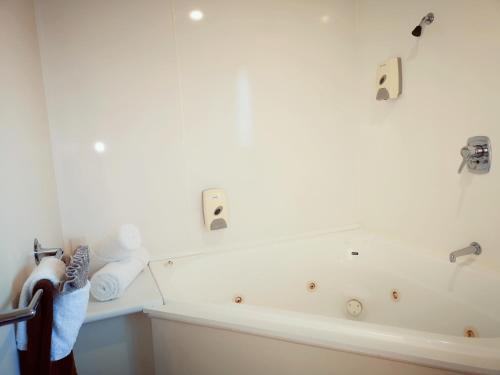 a bathroom with a bath tub and a sink at Aston Court Motel in Blenheim