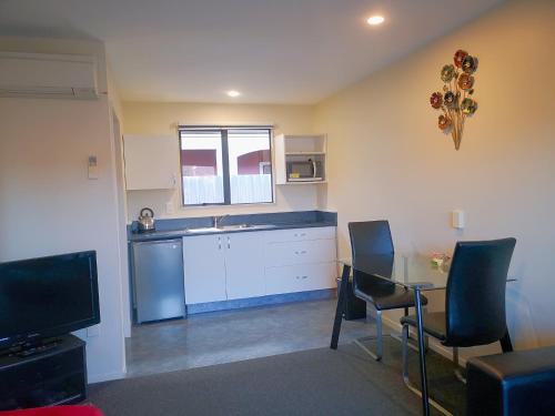 a kitchen with a table and chairs and a counter top at Aston Court Motel in Blenheim