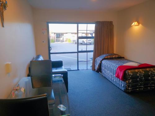 a hotel room with a bed and a glass table at Aston Court Motel in Blenheim