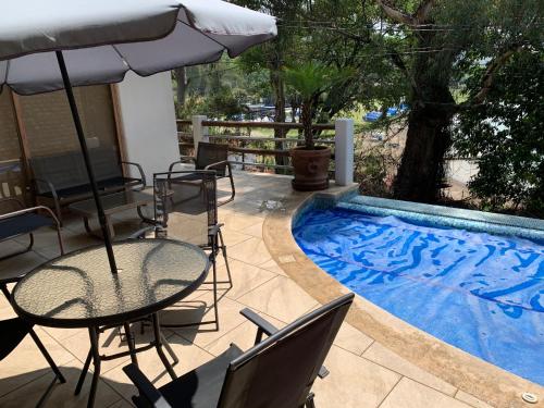patio con tavolo, ombrellone e piscina di Casa Belmez a Valle de Bravo