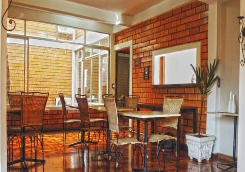 a dining room with a brick wall and a table and chairs at GUEST HOUSE LA MANSIÓN in Foz do Iguaçu