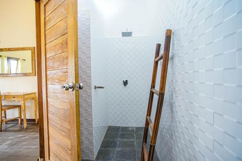 een douche in een kamer met een bakstenen muur bij Bali Manik Guest House Canggu in Canggu