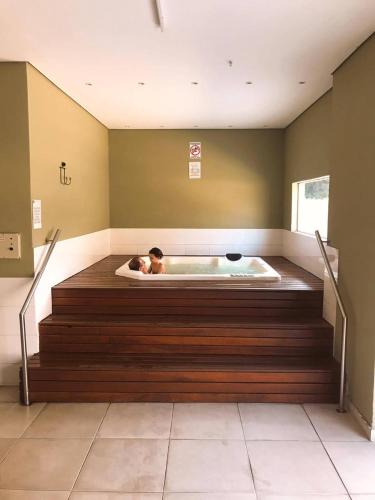 a man laying in a bath tub in a room at Live Suites Itaipava in Itaipava