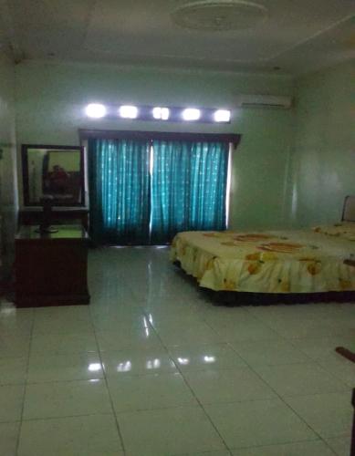 a bedroom with a bed and a window with blue curtains at Hotel Mulia in Lawean