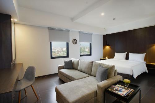 een hotelkamer met een bed en een bank bij Malioboro Prime Hotel in Yogyakarta