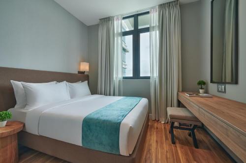 a hotel room with a bed and a desk and a window at Mercure Living Putrajaya in Putrajaya