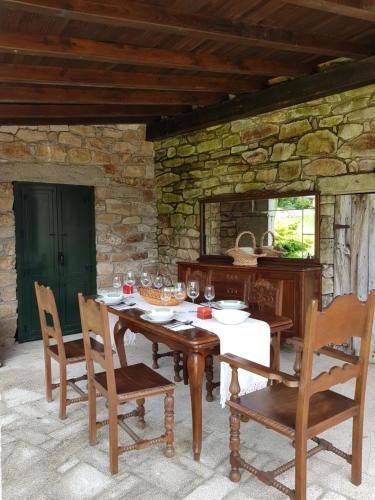 a wooden table and chairs in a stone room at Casa de Lela in Negreira