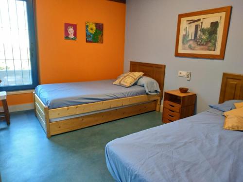 two beds in a room with orange walls at Casa Rural Madre del Agua. Finca El Robledillo in Monesterio
