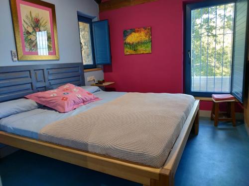 a bedroom with a large bed with pink walls at Casa Rural Madre del Agua. Finca El Robledillo in Monesterio