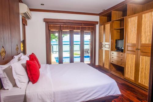 um quarto com uma cama branca e uma almofada vermelha em Pao Jin Poon Villa em Lamai