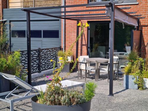 a patio with a table and chairs and plants at Le Berc'AYE in Aye