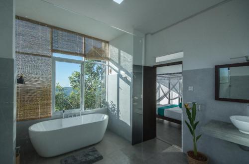 La salle de bains est pourvue d'une baignoire, d'un lavabo et d'une fenêtre. dans l'établissement Treehouse Chalets, à Belihuloya