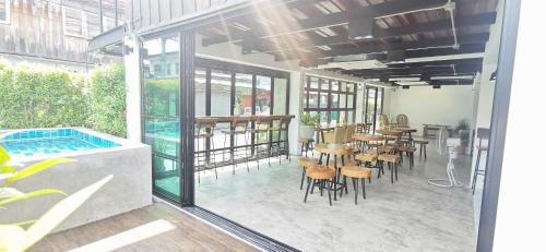 un patio con mesas y sillas y una piscina en Stay Here Hostel en Chiang Mai