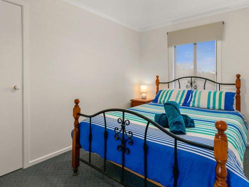 a bedroom with a bed with blue sheets and a window at Waikiki Views in Smiths Beach