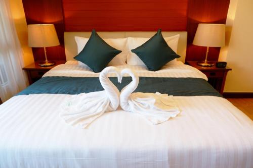 two white swans are sitting on a bed at 42Grand Residence in Bangkok