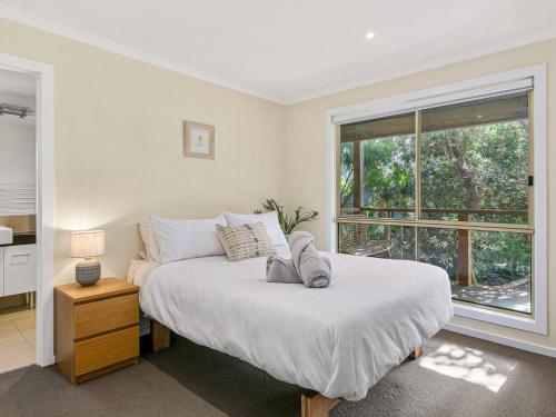 a bedroom with a large bed and a window at The Deck House in Smiths Beach