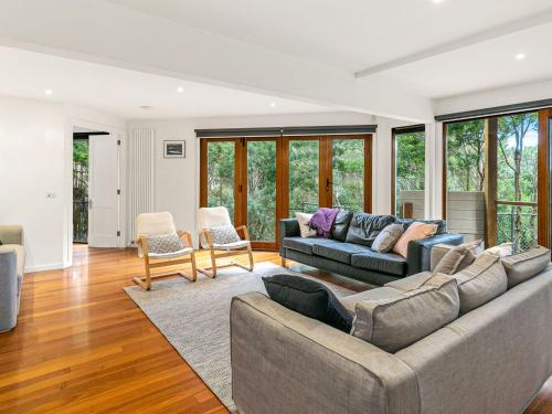a living room with a couch and chairs and windows at The Deck House in Smiths Beach