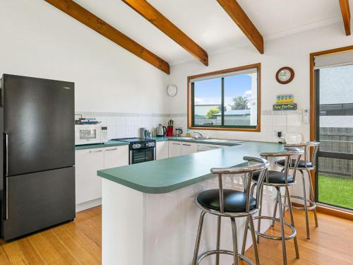 a kitchen with a refrigerator and a counter with stools at Surf Rest'n Bay in Cape Woolamai