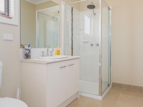 een witte badkamer met een douche en een wastafel bij Seaside Splendour in Cowes