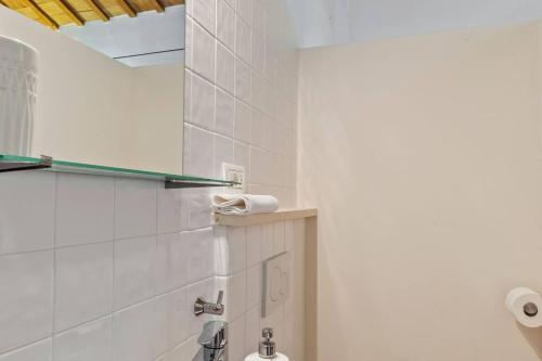 a bathroom with white tiled walls and a toilet at Casali Marchigiani - Ville vacanza private con piscina in Ostra