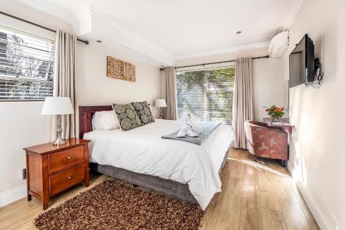 a bedroom with a bed and a tv and a window at The Haystack On Homestead in Johannesburg