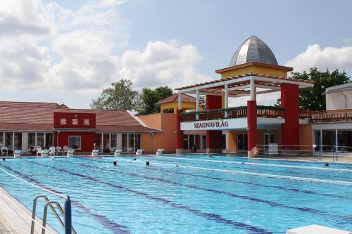 a large swimming pool in front of a building at Írisz Apartmanház in Mórahalom