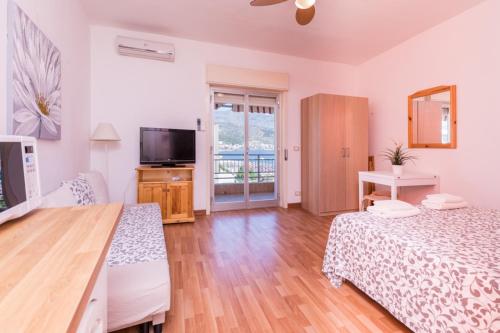 een grote slaapkamer met 2 bedden en een televisie bij Belvedere Naxos 9 in Giardini Naxos