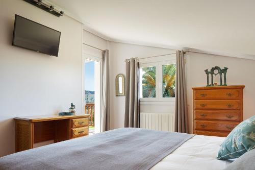 a bedroom with a bed and a dresser and a television at Casa Rural La Palmera - Landetxea in Lasarte