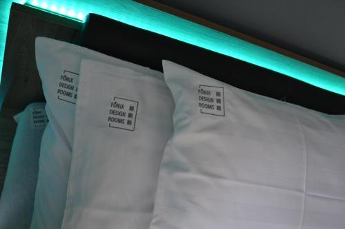 a bed with white pillows with labels on them at Főnix Design Rooms in Debrecen
