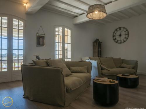 a living room with a couch and a clock on the wall at Les Garrigues de la Vallée des Baux in Paradou