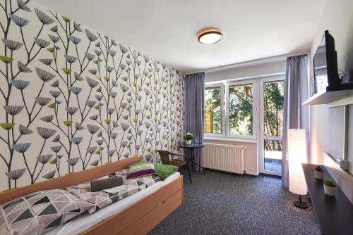 1 dormitorio con cama y pared con estampado de flores en KAMION Ośrodek Wypoczynkowy, en Wierzchlas