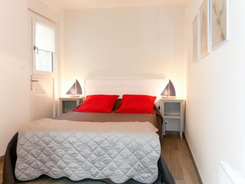 une chambre avec un lit avec deux oreillers rouges dans l'établissement maison au bord de la mer, à Plouhinec