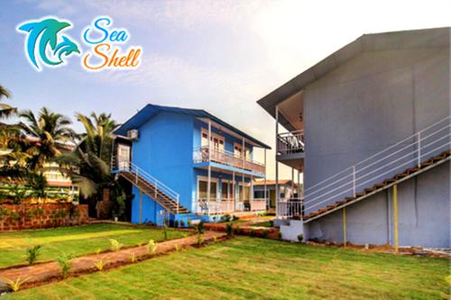 a blue house with a yard next to a building at Sea Shell Beach Cottages & Suites in Arambol