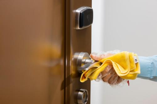 a person with a yellow cleaning glove holding a door knob at Action Hotel Ras Al Khaimah in Ras al Khaimah