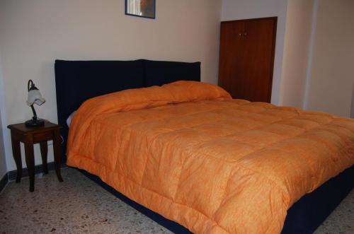 1 cama con edredón naranja y mesa auxiliar en casa susanna en Matino