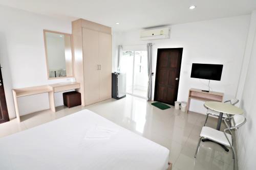a white living room with a table and a tv at Hua Hin Irooms in Hua Hin