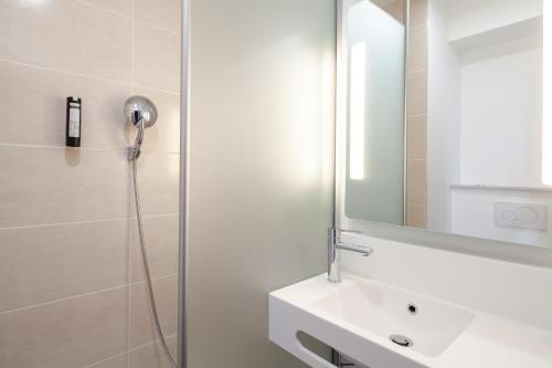 uma casa de banho com um chuveiro, um lavatório e um espelho. em B&B HOTEL Massy Gare TGV em Massy
