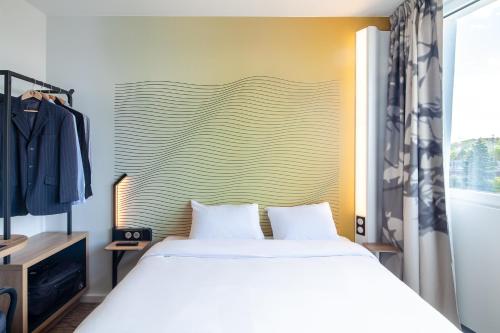 a bedroom with a white bed and a large headboard at B&B HOTEL Massy Gare TGV in Massy