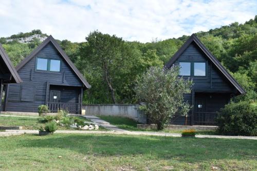 a black house with two windows and a yard at Aparthotel Koliba in Nik&scaron;ić