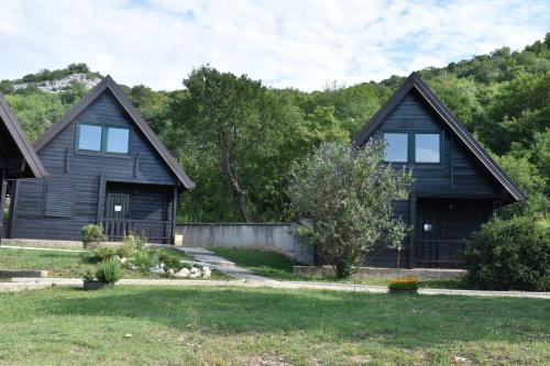 a black house with two windows and a yard at Aparthotel Koliba in Nikšić