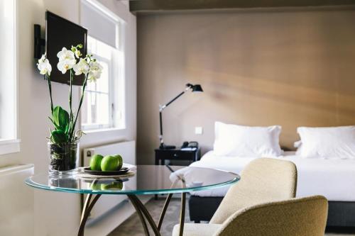 a hotel room with a bed and a glass table with a coffee table at The Dylan Amsterdam - The Leading Hotels of the World in Amsterdam