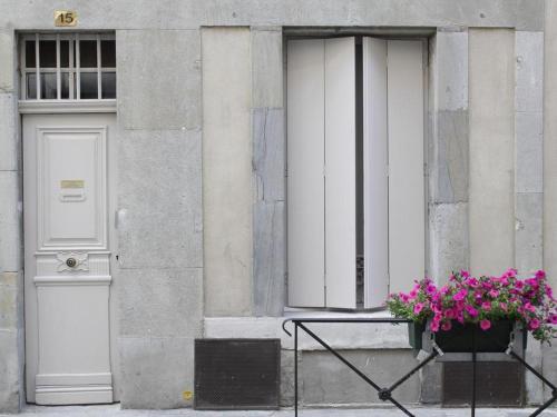 un edificio con due porte e un vaso di fiori con fiori viola di Le relais de la maison Bacou a Carcassonne