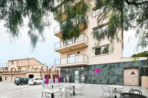 a group of tables and chairs in front of a building at Hotel H in Granollers
