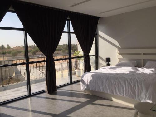 ein Schlafzimmer mit einem Bett und einem großen Fenster in der Unterkunft Chalet Le Porto in Unaizah